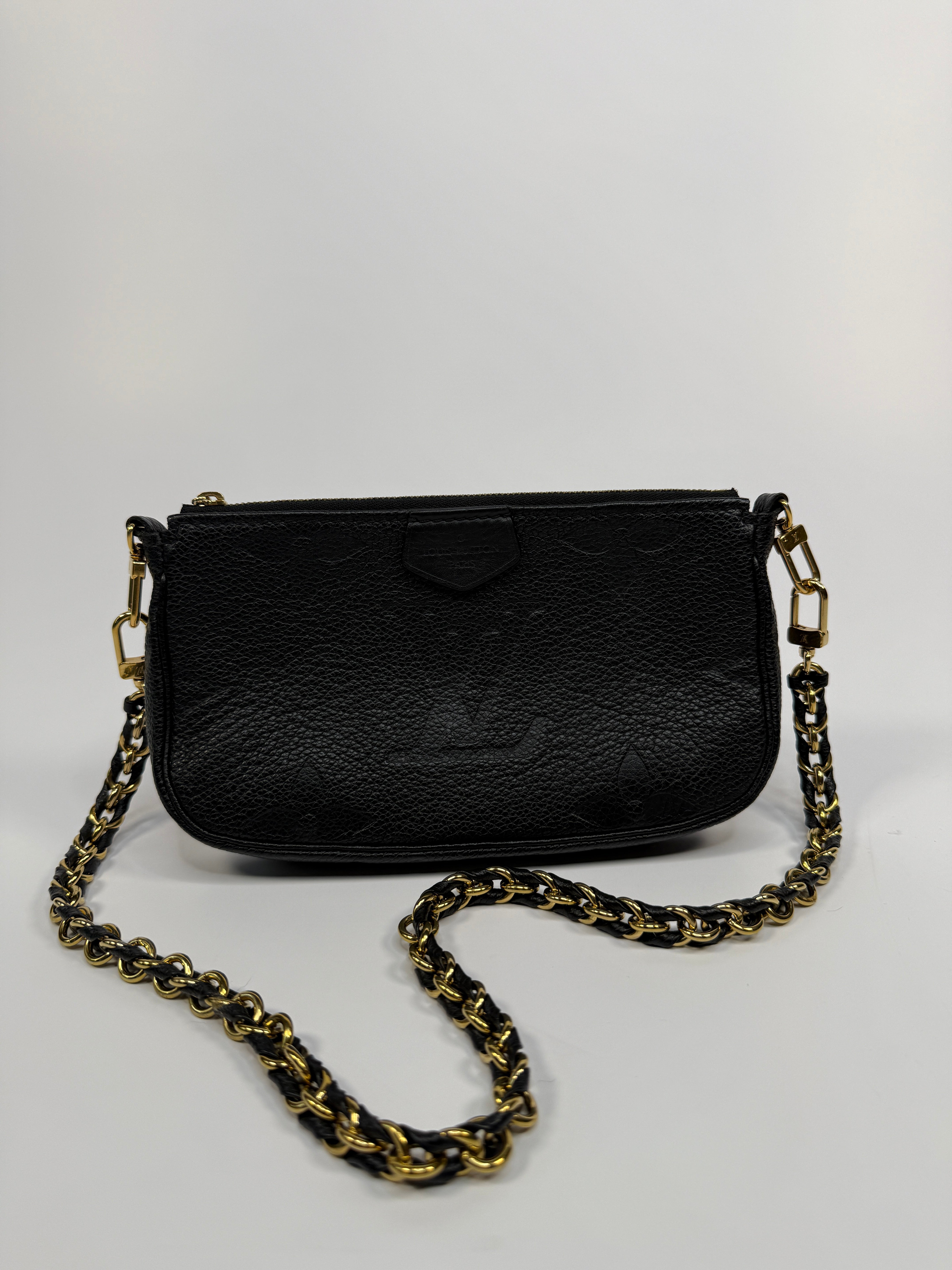 Black handbag with a gold chain strap on a white background