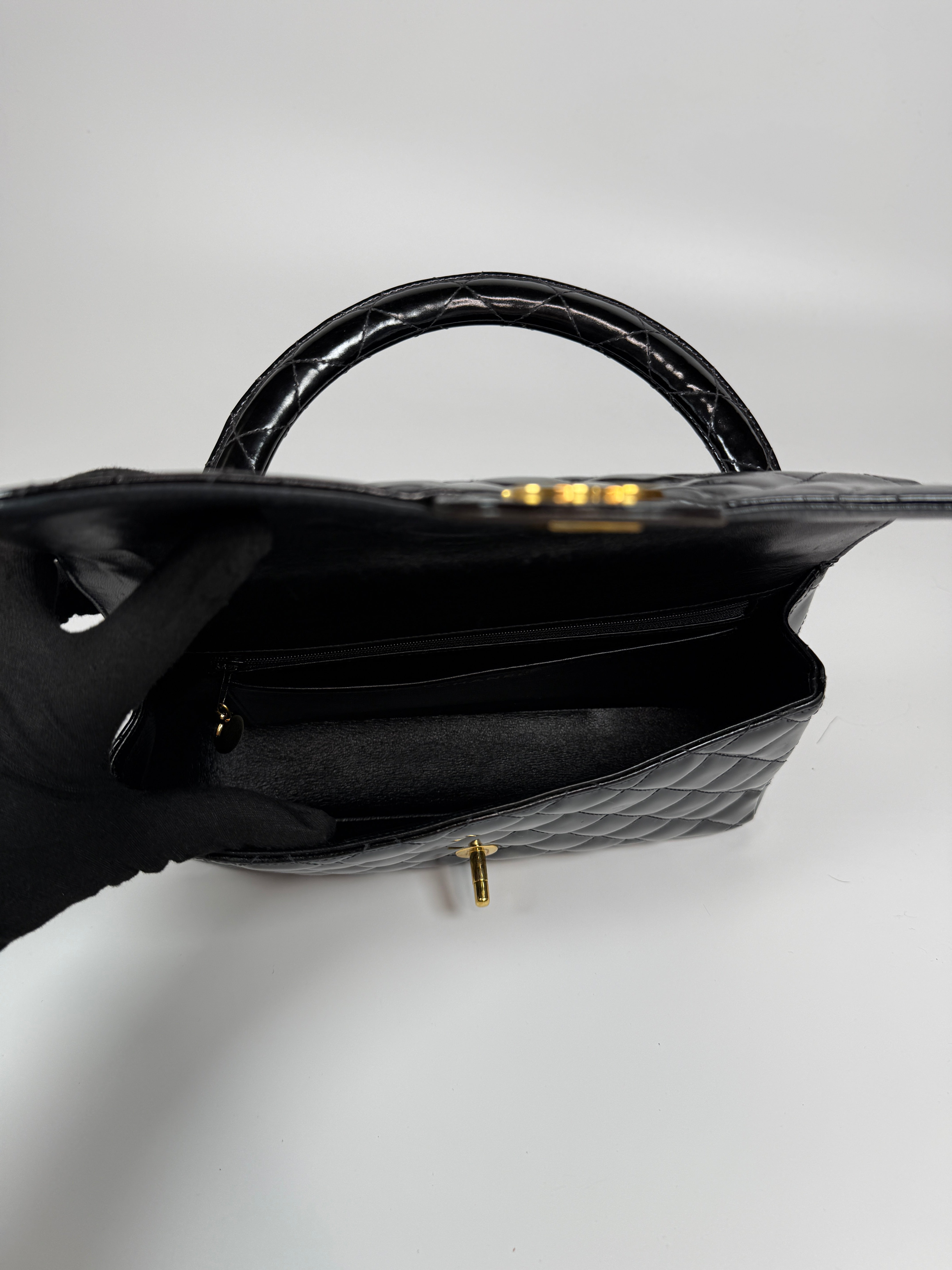 Authentic and preloved Chanel Vintage Kelly Top Handle Bag In Black Patent Leather With 24kt Gold Hardware. Very Good condition. 100% Authenticity guarantee