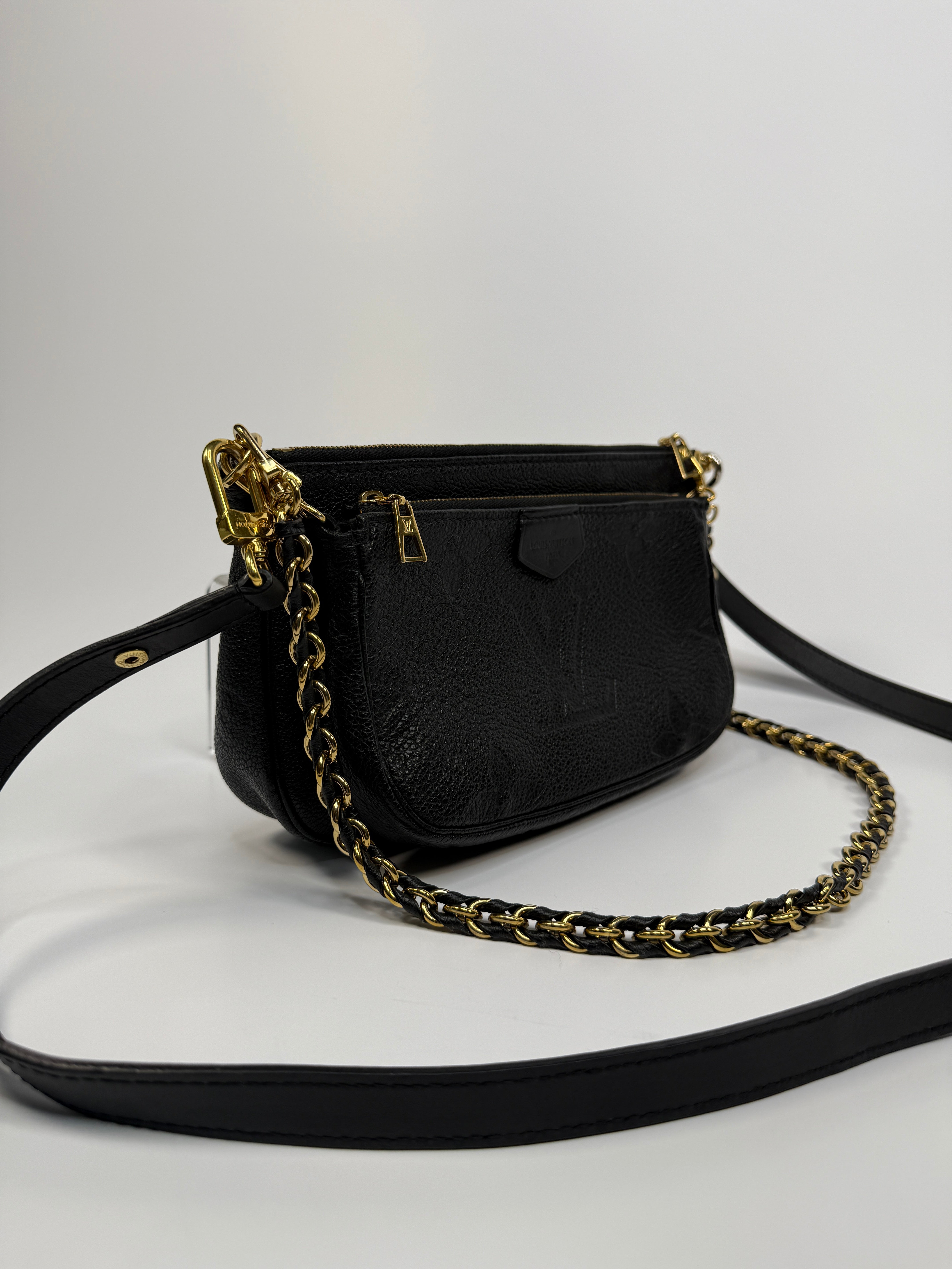 Black handbag with gold chain strap on a white background