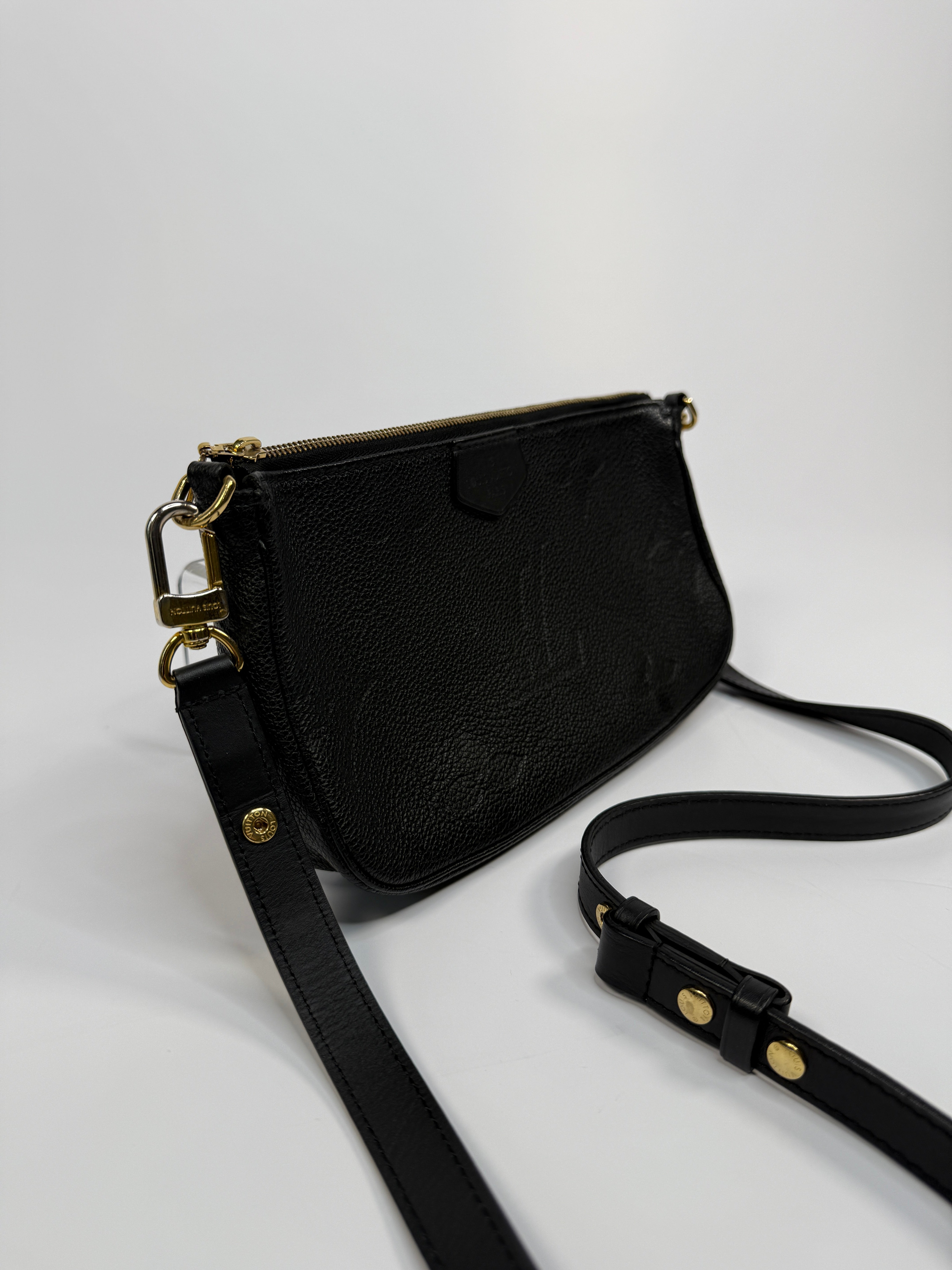 Black handbag with gold accents on a light gray background