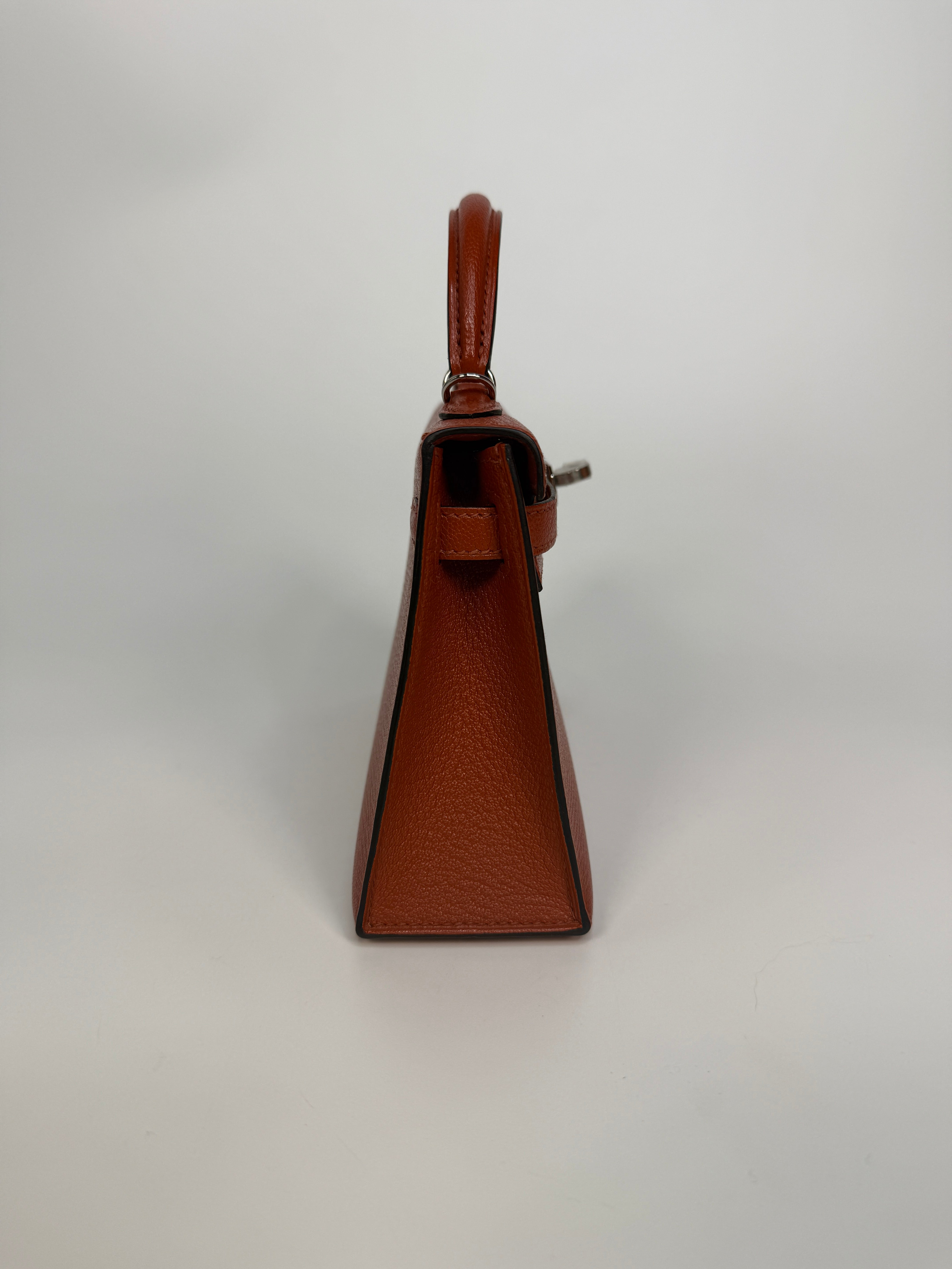 Hermès Mini Kelly In Cuivre Chèvre Mysore Leather With Palladium Hardware. Authentic and preloved in new and unused condition