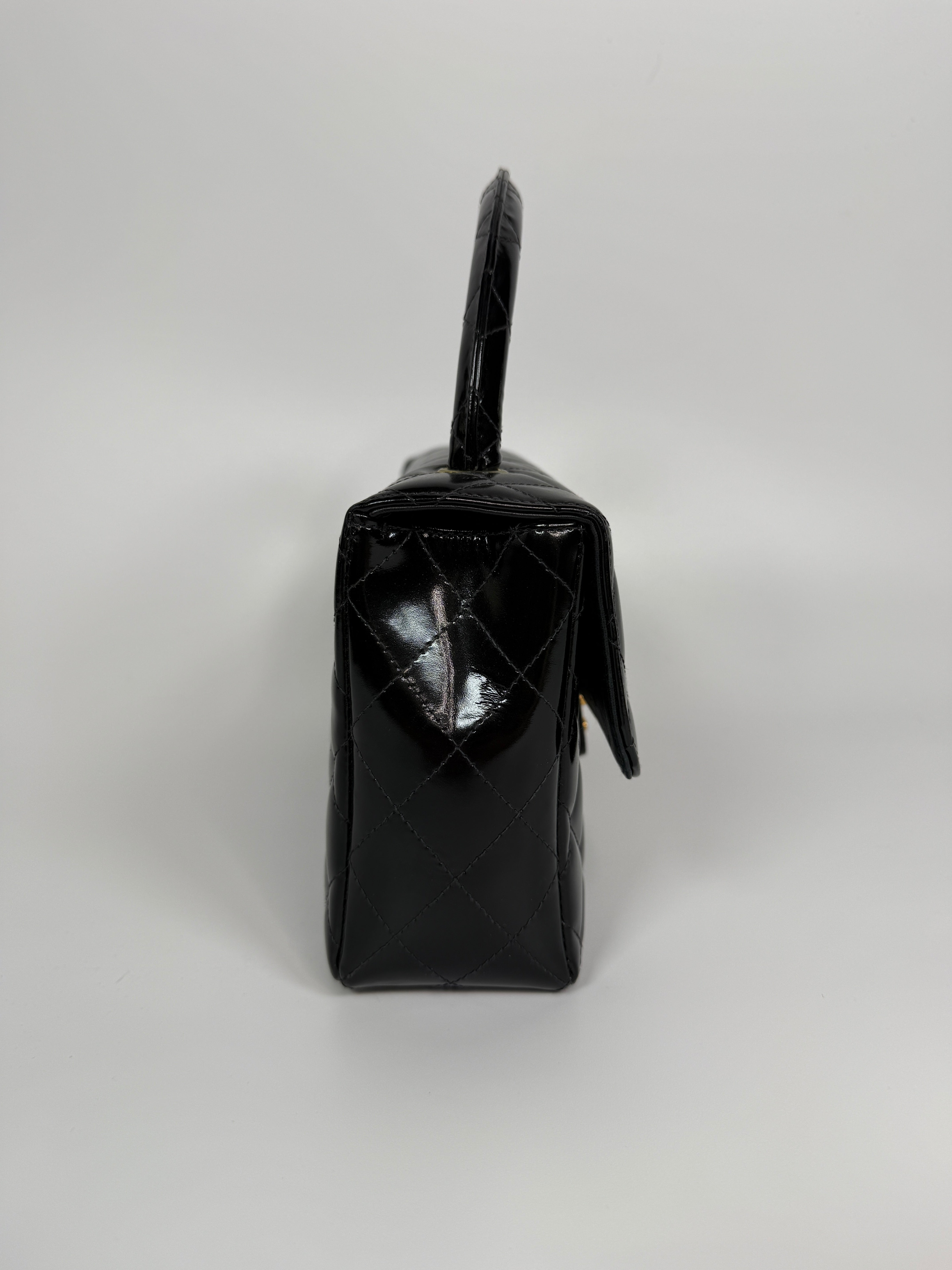 Authentic and preloved Chanel Vintage Kelly Top Handle Bag In Black Patent Leather With 24kt Gold Hardware. Very Good condition. 100% Authenticity guarantee 