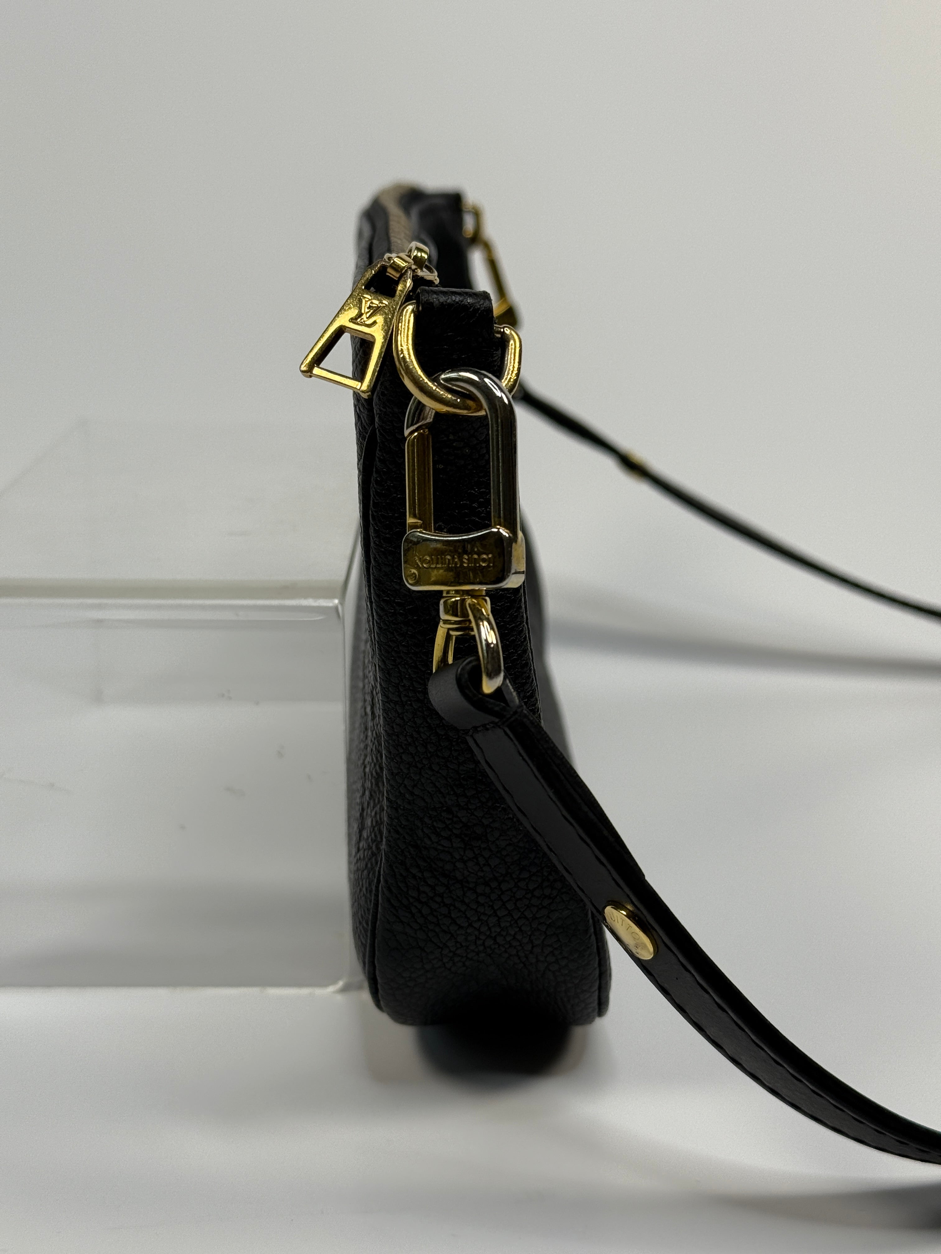 Black leather strap with gold hardware on a white background