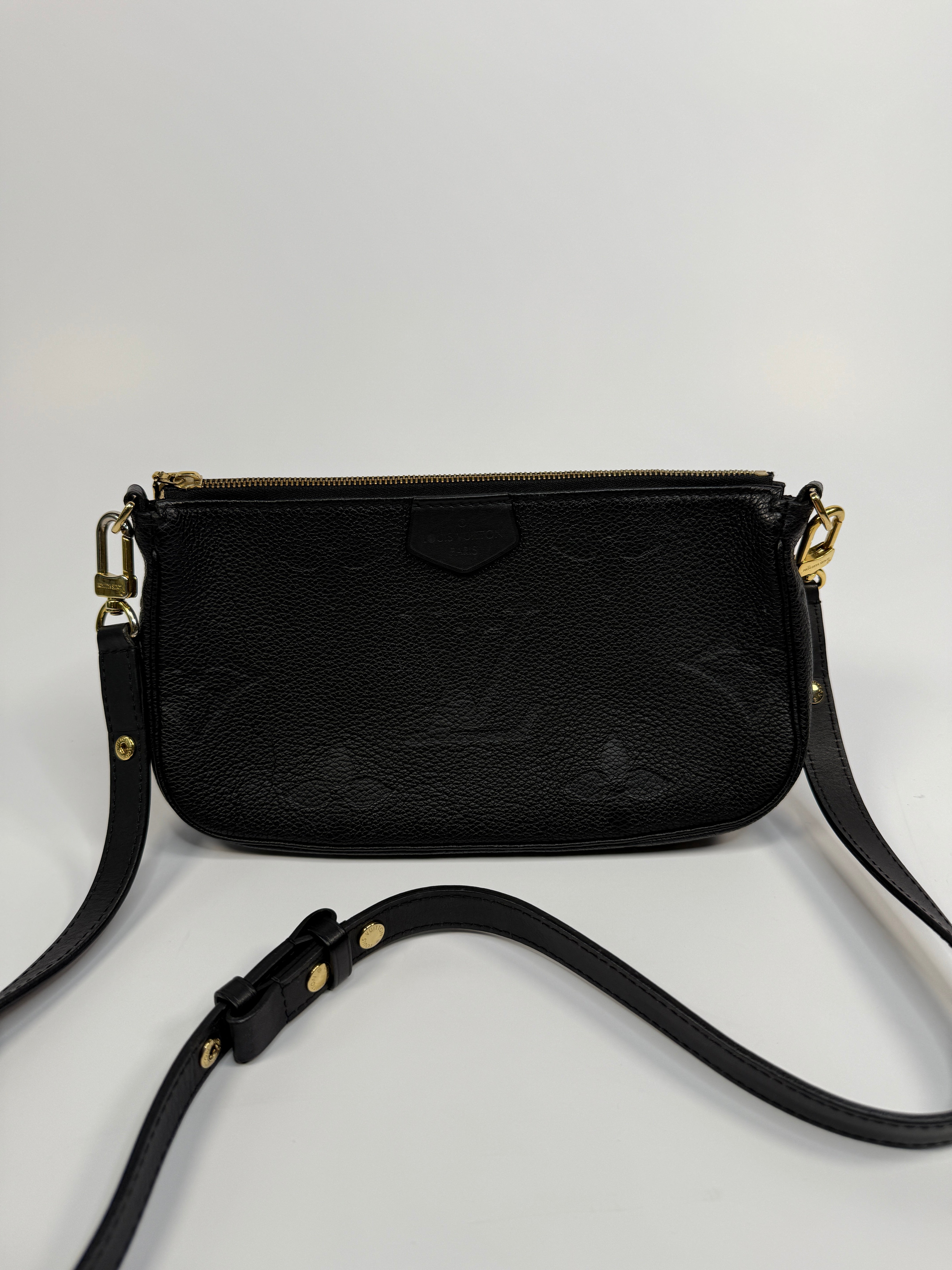 Black leather crossbody bag with gold accents on a light gray background