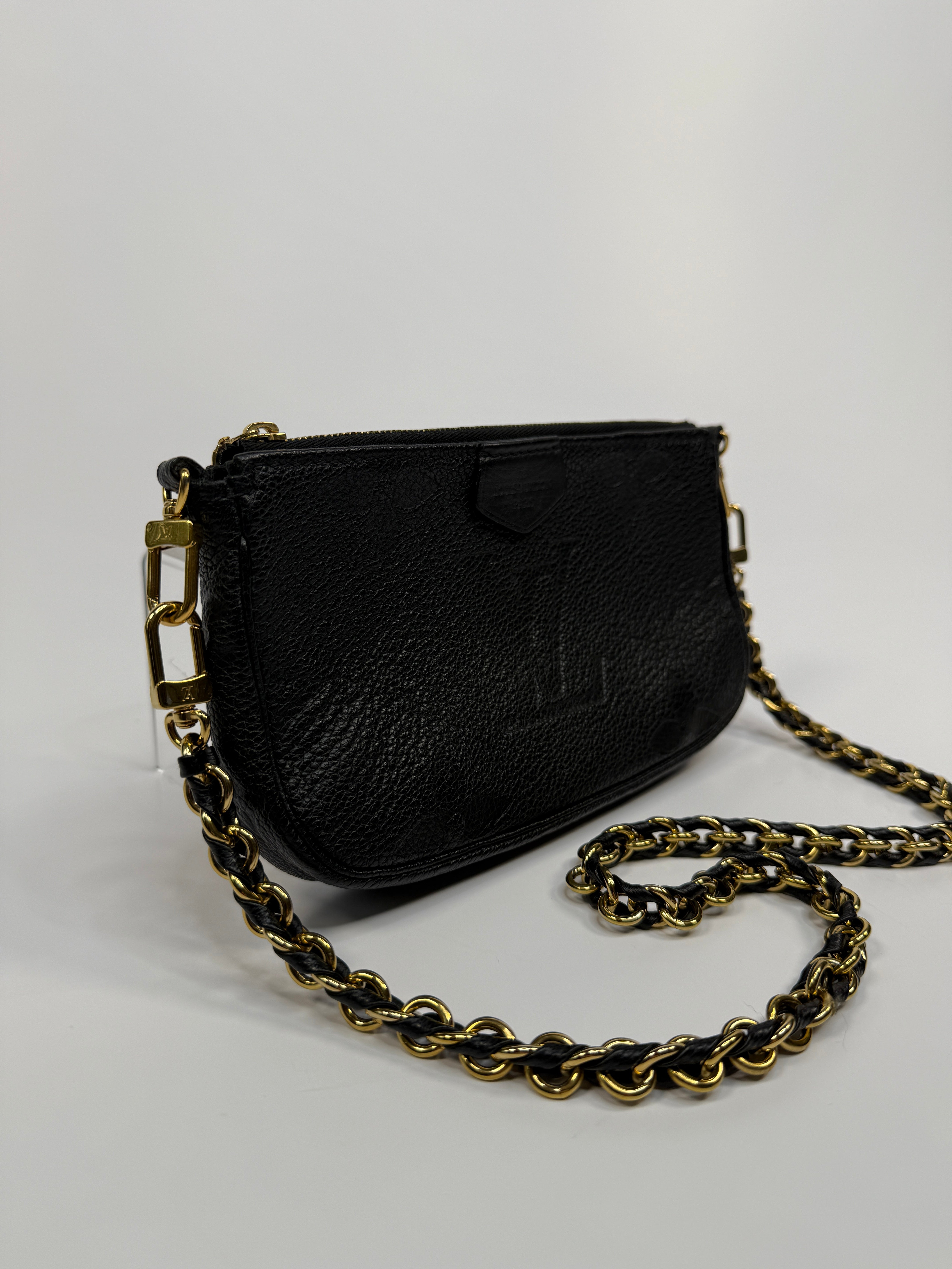 Black leather pouch with gold chain on a white background