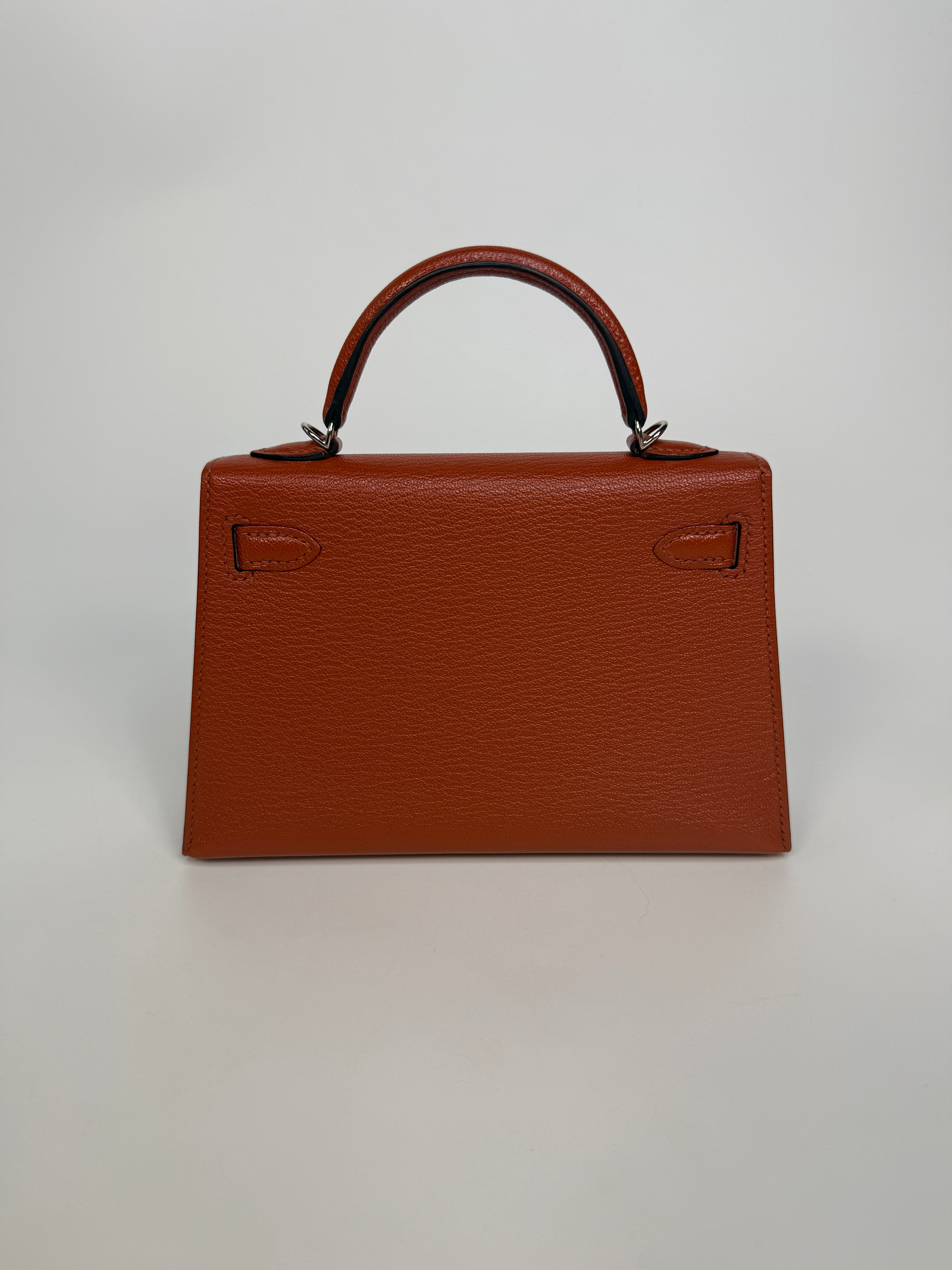 Hermès Mini Kelly In Cuivre Chèvre Mysore Leather With Palladium Hardware. Authentic and preloved in new and unused condition
