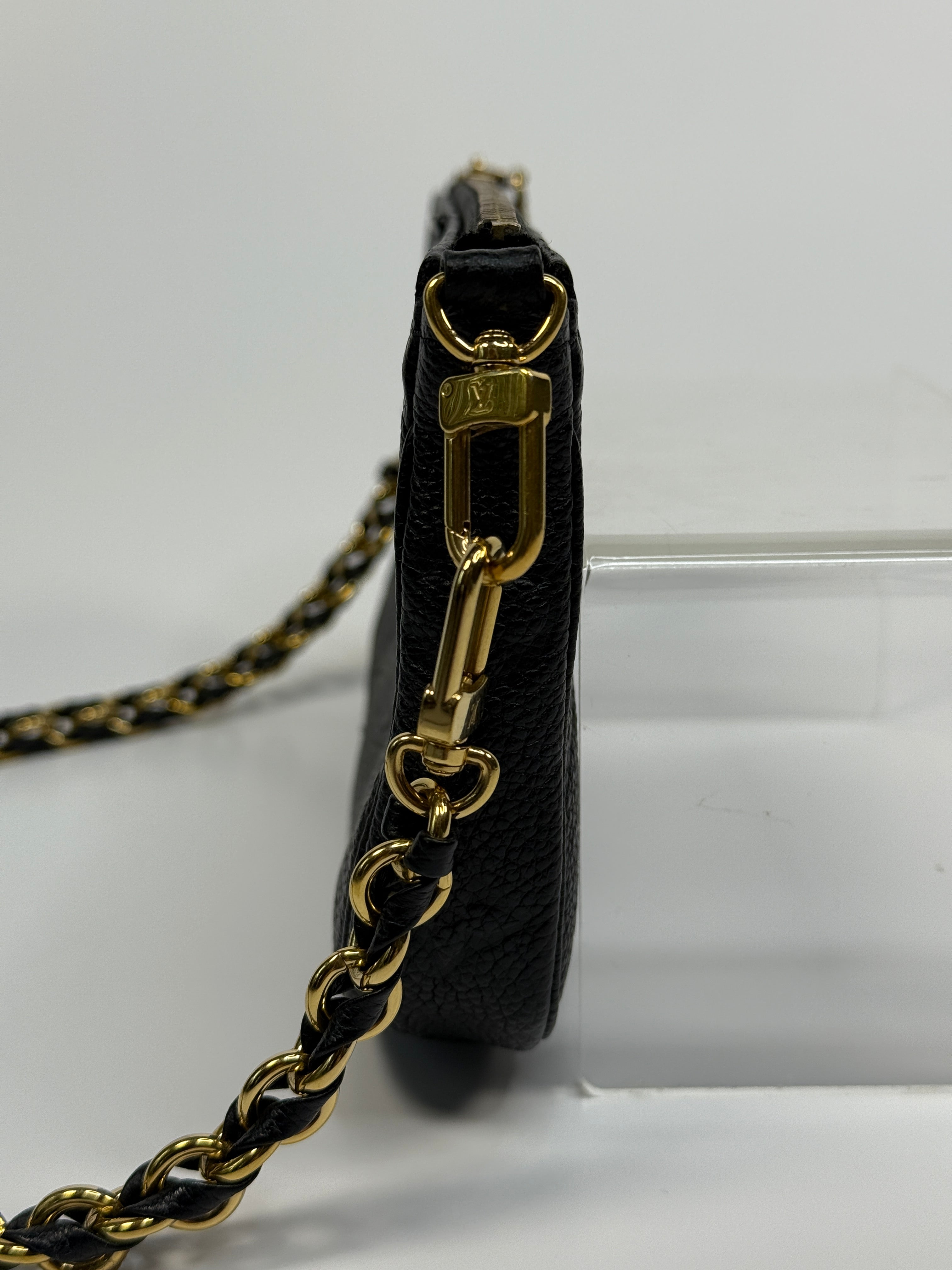 Black handbag with gold chain strap on a white background