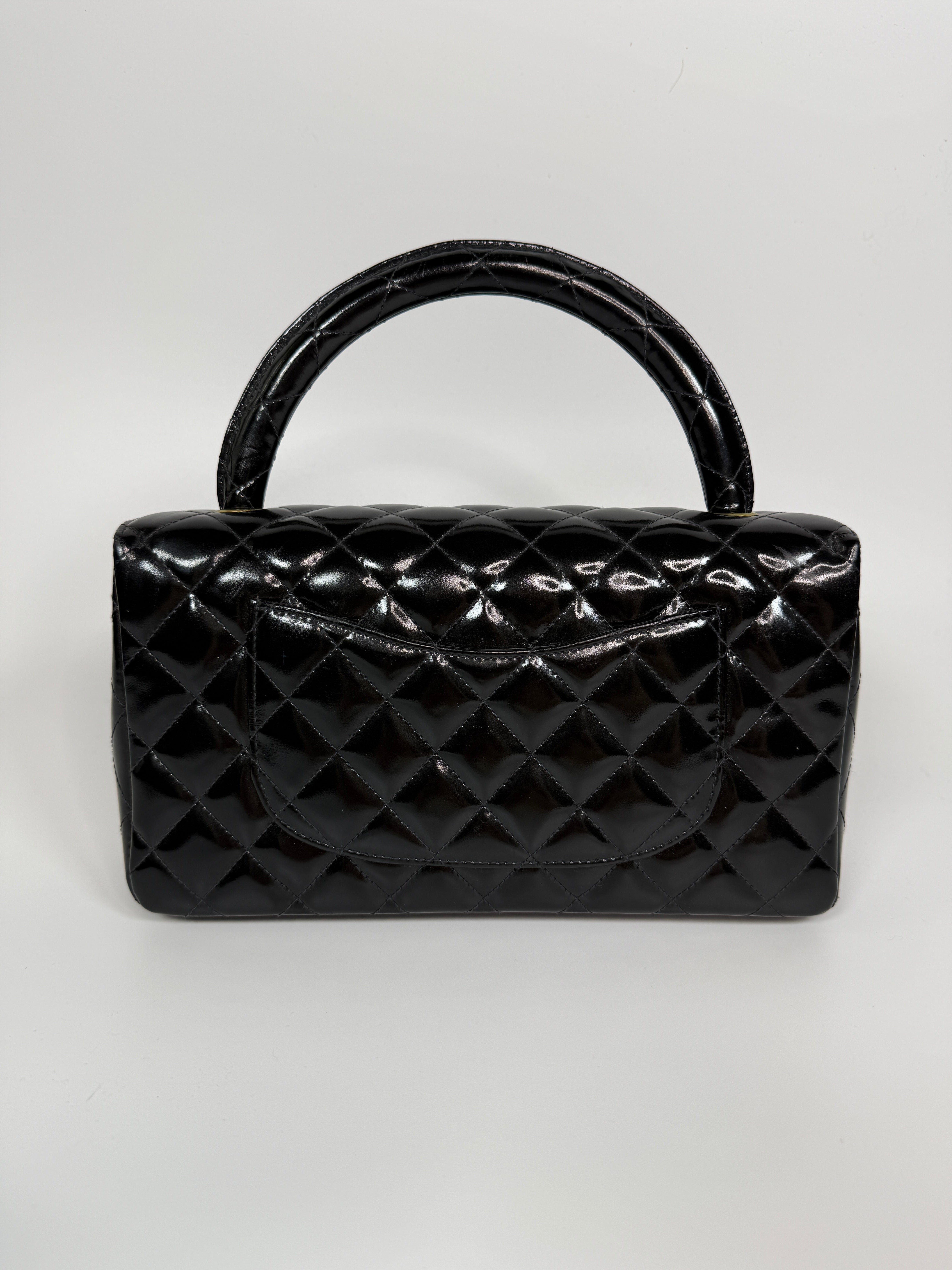 Authentic and preloved Chanel Vintage Kelly Top Handle Bag In Black Patent Leather With 24kt Gold Hardware. Very Good condition. 100% Authenticity guarantee 