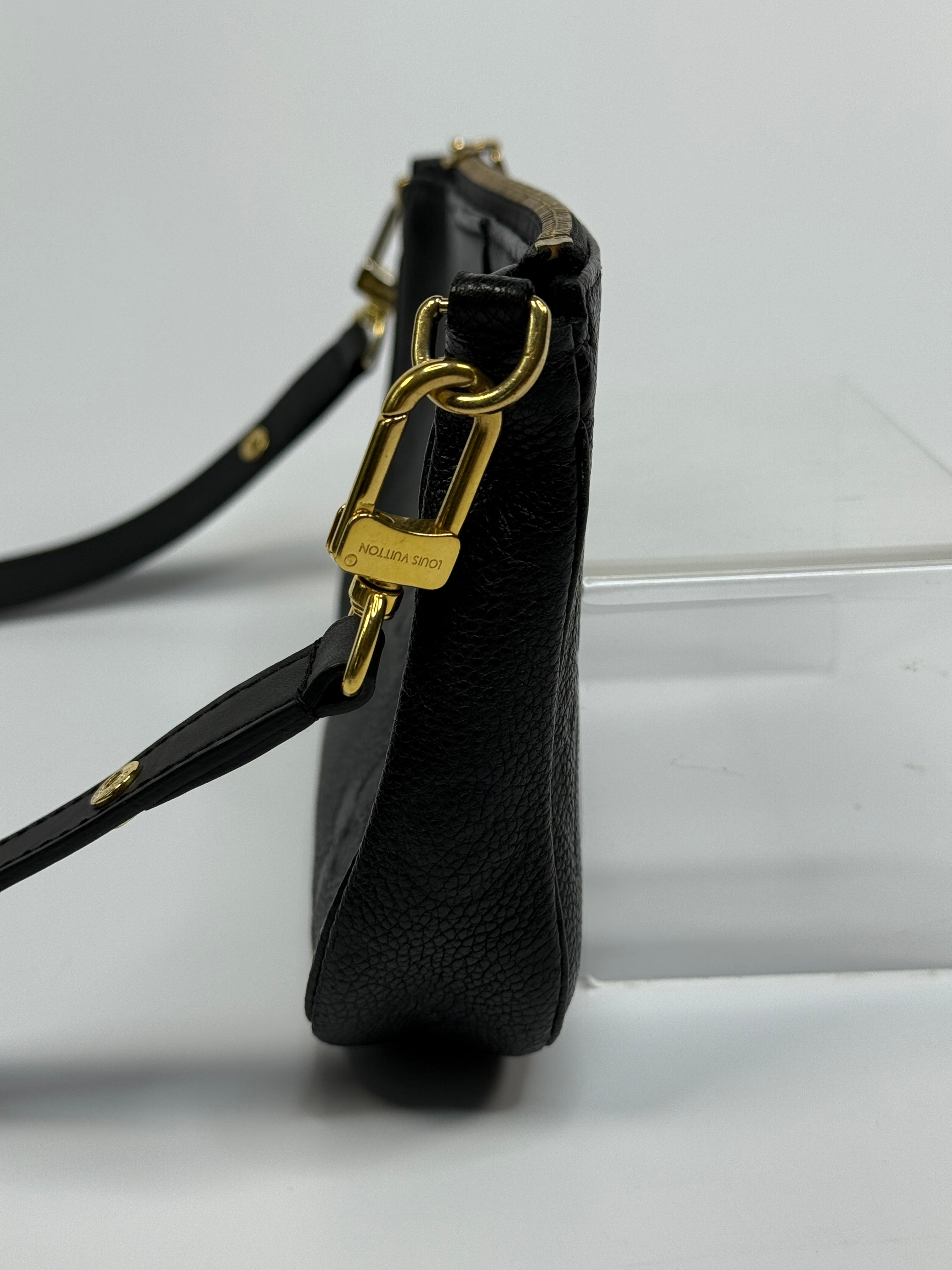 Black leather strap with gold hardware on a white background